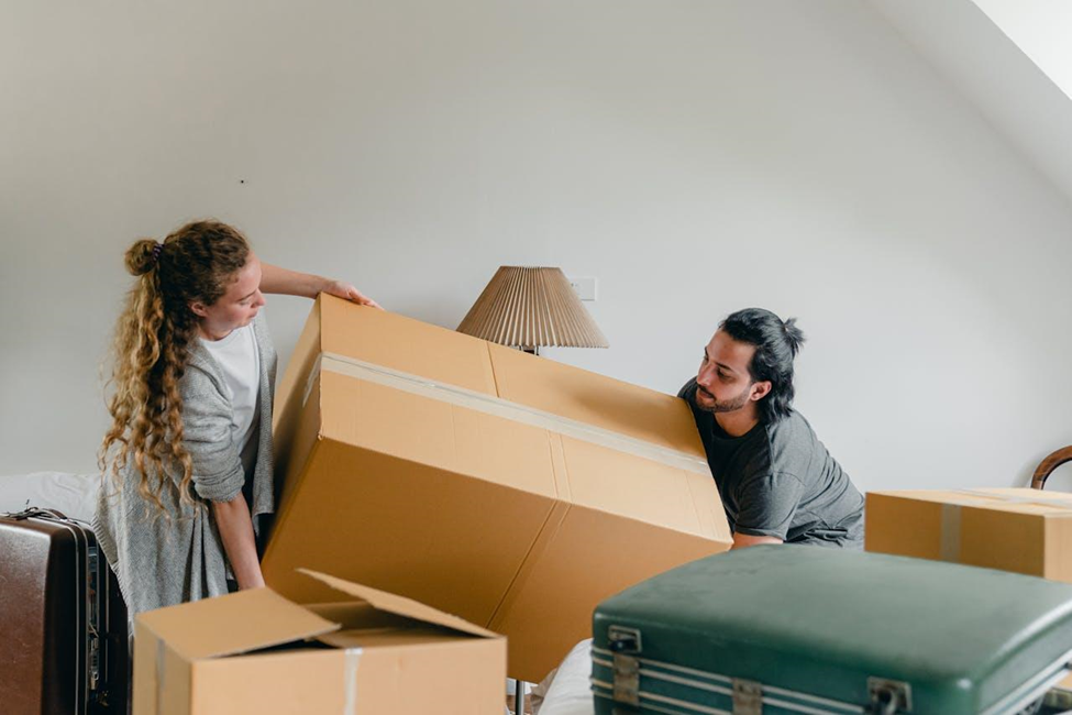 Couple lifting heavy cardboard box while moving